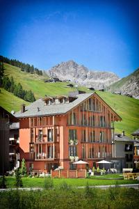 a large building with a mountain in the background at Hotel Roberta Alpine Adults only in Livigno