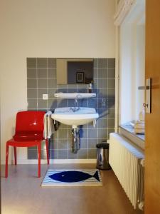 a bathroom with a sink and a red chair at B+B GOLF SCHILDE in Schilde