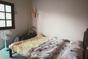 1 cama no hecha en un dormitorio con ventana en Chill Pill Hostel, en Chiang Khan