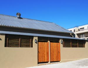 Casa con puertas de madera y techo de metal en Gansbaai Central Accommodation, en Gansbaai