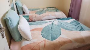 2 Betten mit Kissen und eine Decke mit Blättern drauf in der Unterkunft Mdzimba Mountain Lodge in Ezulwini