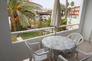 einen Balkon mit einem Tisch, Stühlen und einem Sonnenschirm in der Unterkunft Apartamentos Ecuador in Playa del Ingles