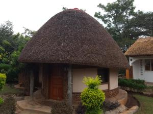 una pequeña casa con techo de paja y puerta en Brownstone Country Home, en Lira