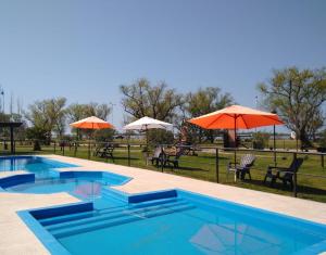 a swimming pool with umbrellas and tables and chairs at Carpe Diem in Ramallo
