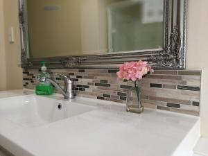 lavabo con espejo y jarrón de flores en Holiday Home in Papamoa, en Tauranga