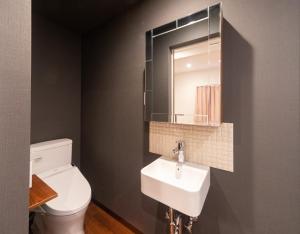 a bathroom with a toilet, sink and mirror at Kagura White Horse Inn in Yuzawa
