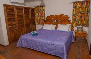 a bedroom with a bed with a purple bedspread at HOTEL VILLA AZUL in Barra de Navidad