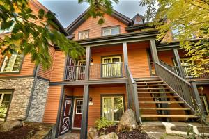 una casa naranja con una escalera delante de ella en Les Manoirs by Rendez-Vous Mont-Tremblant, en Mont-Tremblant