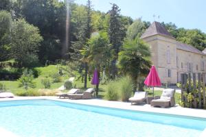 a swimming pool with chairs and umbrellas next to a house at Château de Courtebotte in Saint-Jean-de-Blaignac