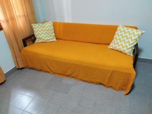 uma cama laranja com duas almofadas em cima em Departamento centrico en Posadas, garage opcional D4 em Posadas