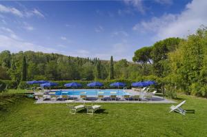 a swimming pool with blue umbrellas and chairs and a pool at Villa Sestilia Guest House in Montaione