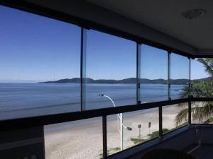 a room with a view of a beach and the ocean at Apartamento Frente Mar Meia Praia in Itapema