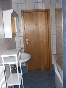 La salle de bains est pourvue d'une porte en bois et d'un lavabo. dans l'établissement Eifel Lodge, à Butgenbach