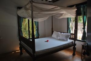 
a bed with a canopy on top of it at Shella White House in Lamu
