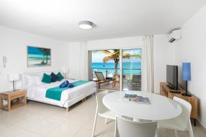 a bedroom with a bed and a dining room with a view of the ocean at Bleu Emeraude Hotel in Grand Case