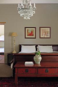 a bedroom with a bed with a table and a chandelier at Joubertsdal Country Estate in Swellendam