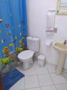 a bathroom with a toilet and a fish shower curtain at Pousada Popeye in Praia de Araçatiba