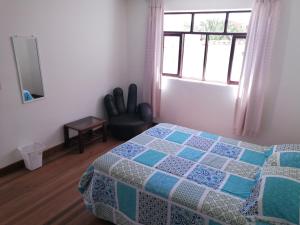 a bedroom with a bed and a window and a chair at Charlies Place in Sucre