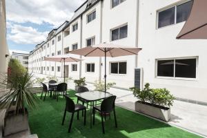 un patio extérieur avec des tables, des chaises et des parasols dans l'établissement Soltigua Apart Hotel Mendoza, à Mendoza