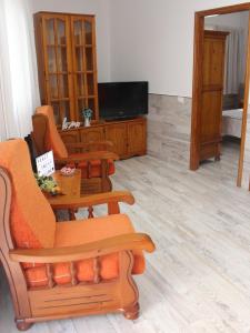 sala de estar con sillas de color naranja y TV en Yanez Sweet Home Valsequillo de GC, en Valsequillo