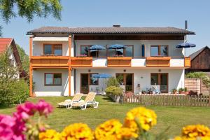 ein Haus mit Stühlen und Sonnenschirmen im Hof in der Unterkunft Haus Christina in Faak am See