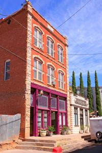 a red brick building with purple trim on a street at Bisbee Brownstone Suites in Bisbee