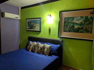 a bedroom with a blue bed with a green wall at Terrakota Apartments in Willemstad