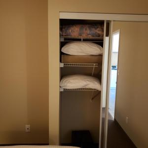 a closet with a stack of white pillows at Shemron Suites Hotel in Deep River