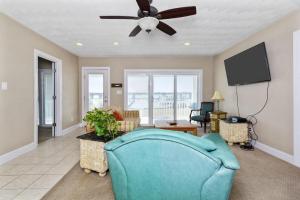 sala de estar con sofá azul y ventilador de techo en Water Front Delight On The Bay Home en Norfolk