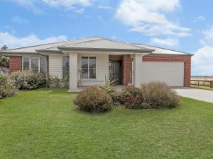 une maison avec un garage et une pelouse dans l'établissement Little Croft, à Port Fairy