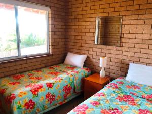 
a bedroom with two beds and two windows at Flat 2 - 3 Bay Lane in Kianga
