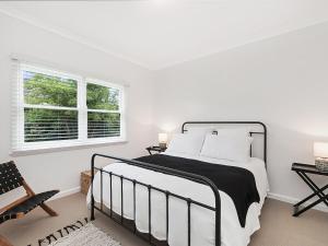 a white bedroom with a bed and two windows at Marlow House in Port Fairy