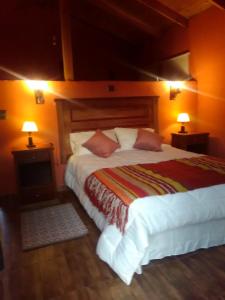a bedroom with a large bed with two lamps on it at Cabañas Terra Pocuro in Los Andes