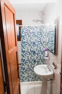 a bathroom with a sink and a shower curtain at Hostel Olimpo House in San Carlos de Bariloche