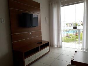 uma sala de estar com uma televisão de ecrã plano numa cómoda em condomínio Mar da Galiléia em Coroa Vermelha