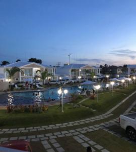 un resort con piscina notturna con luci di condomínio Mar da Galiléia a Coroa Vermelha