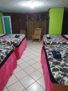 een kamer met 2 bedden en een stoel. bij hotel kasa kamelot 2 in Quetzaltenango