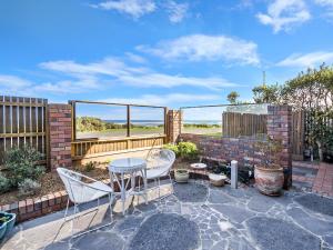 een patio met een tafel en stoelen en een hek bij Pea Soup Beach in Port Fairy