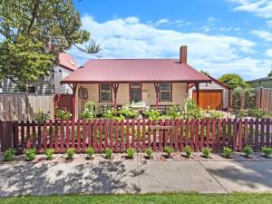 a small house with a fence in front of it at Railway Cottage in Port Fairy