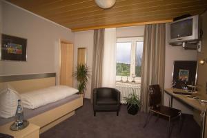 a bedroom with a bed and a chair and a desk at Hotel-Landgasthof Brachfeld in Sulz am Neckar