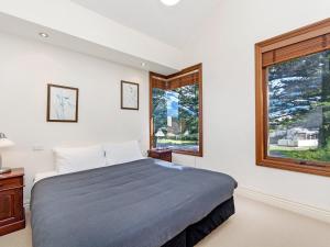 een slaapkamer met een groot bed en 2 ramen bij Shearwater House in Port Fairy
