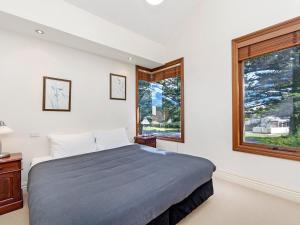 Un dormitorio con una cama grande y dos ventanas. en Shearwater House, en Port Fairy