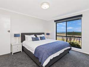 a bedroom with a bed and a large window at Seaclusion in Port Fairy