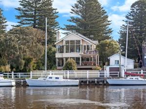 a house on a dock with boats in the water at Shearwater Riverview Apartment in Port Fairy
