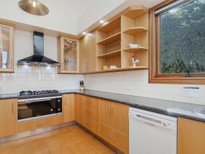 Una cocina con armarios de madera y un fregadero y una ventana. en Shearwater Penthouse, en Port Fairy