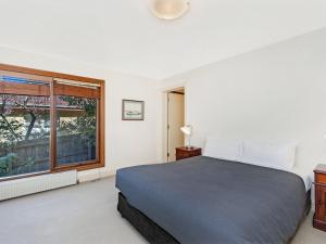 a bedroom with a bed and a window at Shearwater Riverview Apartment in Port Fairy