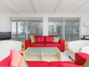 a living room with a red couch and a table at Sheoaks Cottage in Port Fairy