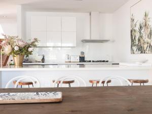 a white kitchen with a wooden table and chairs at Spinnakers Waterfront in Port Fairy