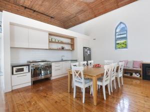 a kitchen with a wooden table and white cabinets at The Church in Port Fairy