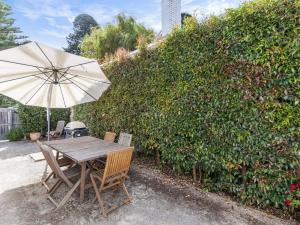 a wooden table with an umbrella next to a hedge at The Church in Port Fairy